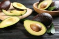 Whole and cut avocados with green leaves on dark wooden table, closeup Royalty Free Stock Photo