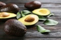 Whole and cut avocados with green leaves on dark wooden table, closeup Royalty Free Stock Photo