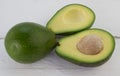 Whole and cut avocados on rustic white wood