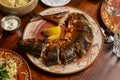 Whole cut fried fish with fresh herbs and lemon on a table for dinner. Whole meal, table covered with food Royalty Free Stock Photo