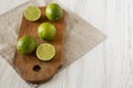 Whole and cut green citrus limes on a rustic wooden board over white wooden background, side view. Copy space Royalty Free Stock Photo