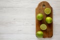 Whole and cut green citrus limes on a rustic wooden board over white wooden background, top view. Copy space Royalty Free Stock Photo