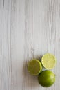 Whole and cut green citrus limes on a white wooden background, top view. Copy space Royalty Free Stock Photo