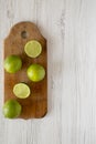 Whole and cut green citrus limes on a wooden board over white wooden surface, top view. Copy space Royalty Free Stock Photo