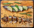 Whole and cut grey mullet fishes lie on light wooden cutting boa Royalty Free Stock Photo