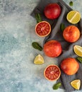 Whole and cut in half blood Sicilian oranges, limes and mint on blue concrete background. Top view. Copy space