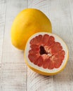 Whole and cut in half juicy grapefruit on a white wooden background. Fruit