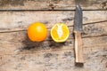 Whole and Cut in Half Orange lying with Knife on Textured Weathered Wooden Table.