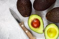 Whole and cut in half ripe organic avocados and a knife on a grey background. The Haas Avocado. Source of vitamins , trace