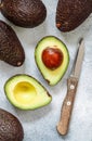 Whole and cut in half ripe organic avocados and a knife on a grey background. The Haas Avocado. Source of vitamins , trace