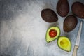 Whole and cut in half ripe organic avocados and a knife on a grey background. The Haas Avocado. Source of vitamins , trace