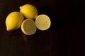 Whole and cut lemons on dark background