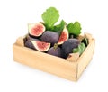 Whole and cut tasty fresh figs with green leaves in wooden crate on background Royalty Free Stock Photo