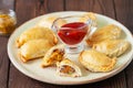 Whole and cutted empanadas with meat and vegetables on a plate with sauces on a wooden background