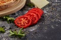 Whole and cutted tomato of pizza on italian black paper table Royalty Free Stock Photo