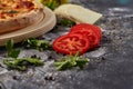 Whole and cutted tomato of pizza on italian black paper table Royalty Free Stock Photo