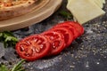 Whole and cutted tomato of pizza on italian black paper table Royalty Free Stock Photo