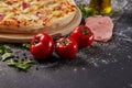 Whole and cutted tomato of pizza on italian black paper table Royalty Free Stock Photo