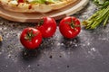 Whole and cutted tomato of pizza on italian black paper table Royalty Free Stock Photo