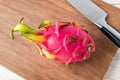 Whole dragon fruit or pitaya and sharp knife on a brown wooden cuttind board. Healthy vegetarian rich in B vitamins and tannin