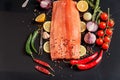 Sliced whole filet with green and red chili peppers, lemon, peas, garlic, cherry tomatoes on a sprig, on ions and rosemary Royalty Free Stock Photo