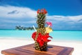 Whole fresh pineapple cocktail with straws, flowers and umbrella on wooden table ocean background at the beach Royalty Free Stock Photo