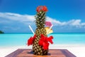 Whole fresh pineapple decorated cocktail with straws, flowers and umbrella on wooden table ocean background at the beach Royalty Free Stock Photo