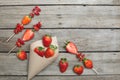 Whole fresh red strawberries scattered of paper cone and sliced strawberries on wooden skewers Royalty Free Stock Photo