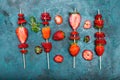Whole fresh red strawberries and sliced strawberries on wooden skewers Royalty Free Stock Photo