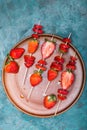 Whole fresh red strawberries and sliced strawberries on wooden skewers in ceramic plate Royalty Free Stock Photo