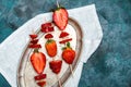 Whole fresh red strawberries and sliced strawberries on wooden skewers on vintage plate Royalty Free Stock Photo