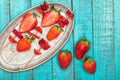 Whole fresh red strawberries and sliced strawberries on wooden skewers in vintage plate on wooden tabletop Royalty Free Stock Photo