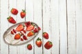 Whole fresh red strawberries and sliced strawberries on wooden skewers in vintage plate on wooden tabletop Royalty Free Stock Photo