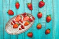 Whole fresh red strawberries and sliced strawberries on wooden skewers in vintage plate on wooden tabletop Royalty Free Stock Photo