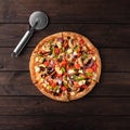 Whole fresh round pizza with chicken meat, vegetables, mushrooms and cheese top view on a wooden brown table Royalty Free Stock Photo