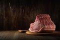 a whole freshly cut piece of raw pork loin lies on a cutting board on a brown wooden background. side view. artistic moody photo