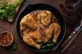 Whole fried chicken tabaka on cast iron pan, old wooden background Royalty Free Stock Photo