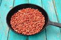 Whole fried pink peanuts in black cast iron pan on turquoise ta Royalty Free Stock Photo