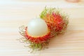 Whole Fruit of Fresh Ripe Rambutan and Peeled to Show Its White Juicy Flesh Isolated on Wooden Table Royalty Free Stock Photo