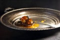 WHOLE FRUIT JAM WITH THICK SYRUP ON A SPOON RESTING ON A METAL PLATTER WITH A PATINA FINISH