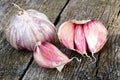 Whole garlic with broken bulb and pink cloves on rustic wooden b
