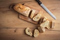 Whole grain bread close-up on the wooden cutting board. Knife with serrated blade. Fresh bread on the wooden kitchen table Royalty Free Stock Photo