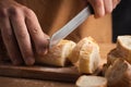 Whole grain bread close-up on the wooden cutting board. Man cutting fresh bread with a big knife Royalty Free Stock Photo