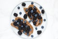 Whole grain bread toasts with peanut butter, blueberries and blackberries on white marble table. healthy breakfast Royalty Free Stock Photo