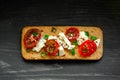 Whole grain cookies, thin crisp bread, with cheese, tomatoes, green onion and flaxes seeds on wood black background