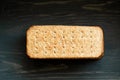 Whole grain cookies, thin crisp bread with spices and herbs on black background.