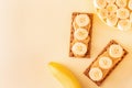 Whole grain crisp bread and peanut butter with banana chunks on pastel yellow background Royalty Free Stock Photo