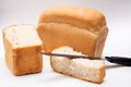 Whole grain loaf and Slices of fresh bread with knife for cut on white background Royalty Free Stock Photo