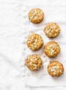 Whole grain mini muffins with dried apricots, oatmeal, apple, carrots and nuts on light background, top view