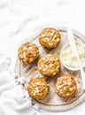 Whole grain muffins with dried apricots, oatmeal, apple, carrots and nuts on rustic cutting board on light background, top view. H
